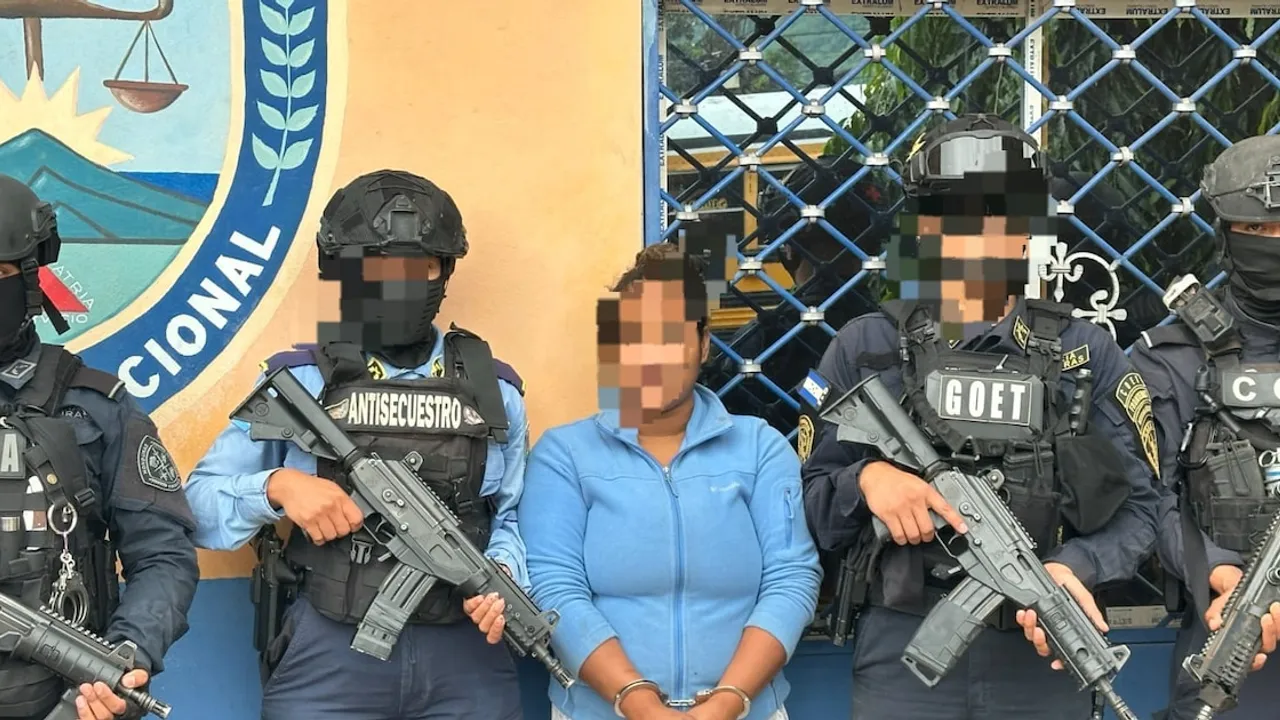 Una mujer esposada permanece custodiada por agentes policiales tácticos armados con fusiles ante un edificio oficial.