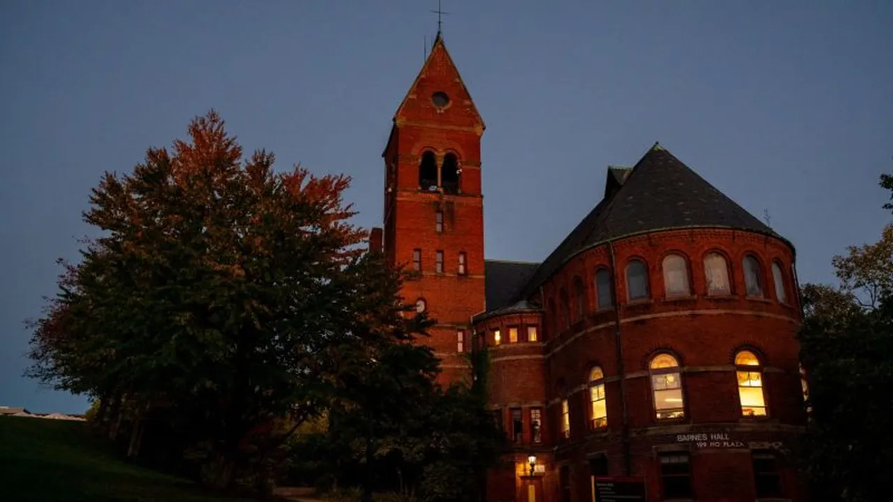Fachada de ladrillo rojo de Barnes Hall con torre y ventanales iluminados al atardecer en Cornell.