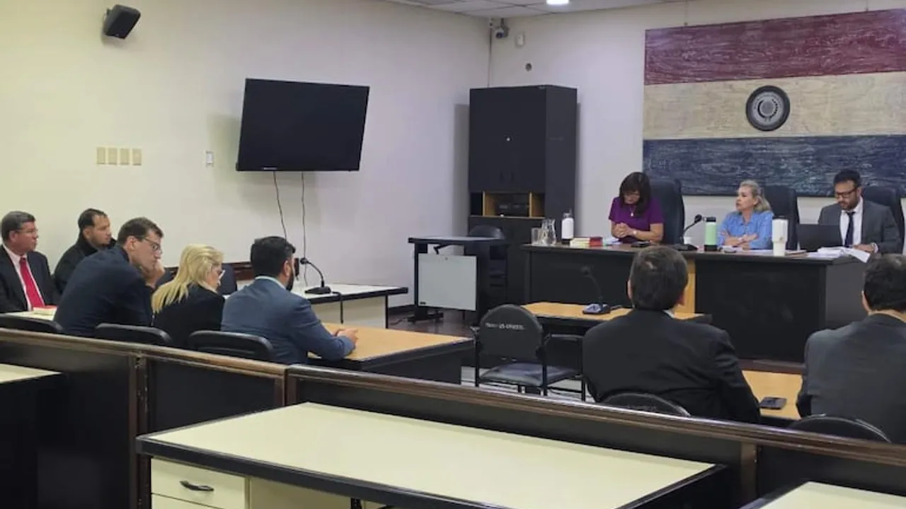 Tres jueces en un estrado judicial escuchan a procesados y abogados durante una audiencia en sala de juicios orales.
