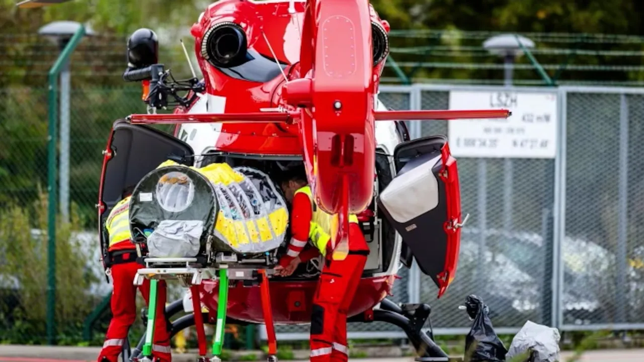 Personal médico de emergencia introduce una cápsula de aislamiento dentro de un helicóptero rojo de rescate.