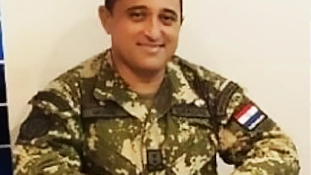 Hombre con uniforme militar de camuflaje y distintivo de la bandera de Paraguay sonríe en primer plano.
