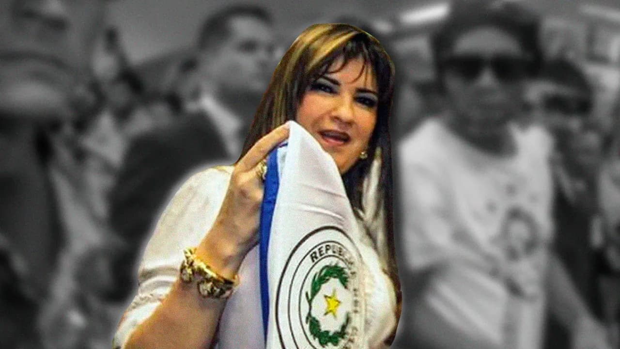 Mujer sosteniendo una bandera paraguaya en primer plano con personas desenfocadas de fondo en un recinto.