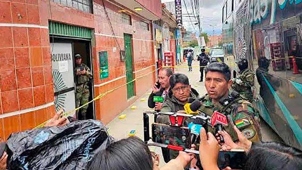 Uniformado con camuflado brinda declaraciones rodeado de micrófonos y prensa en una calle con cordón policial.