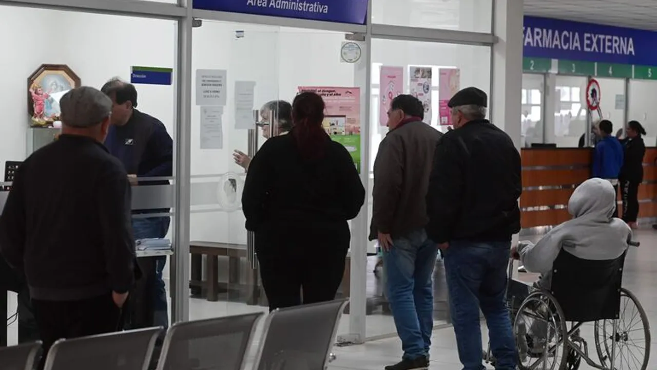 Personas de la tercera edad esperan frente a ventanillas del área administrativa y farmacia de un centro médico