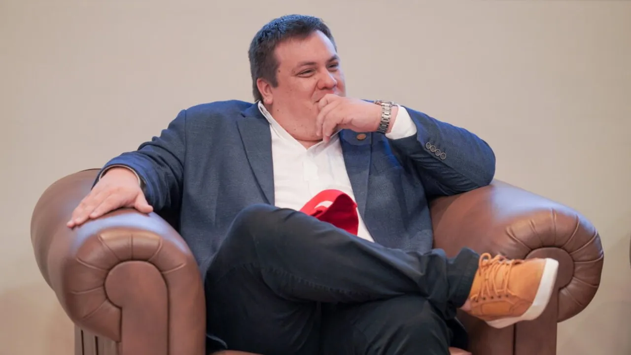 El gobernador César Sosa sonríe sentado en un sillón de cuero marrón con la mano en la barbilla durante un evento.