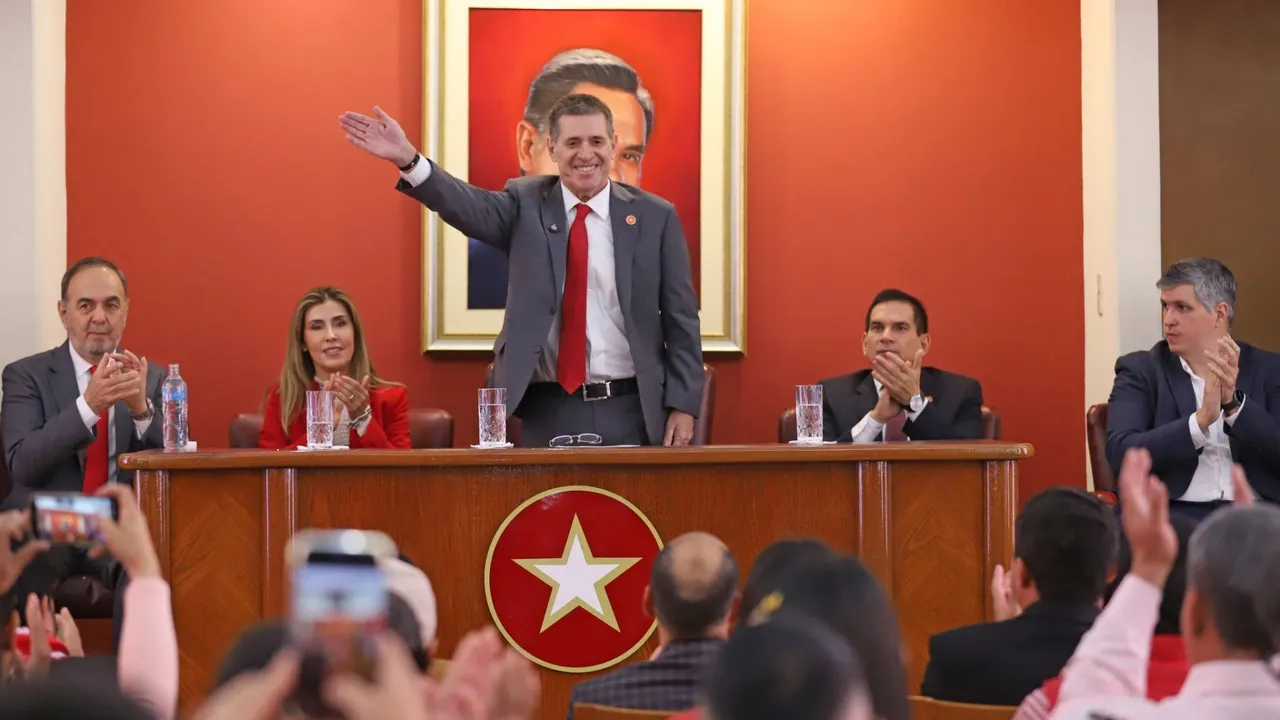 Horacio Cartes saluda de pie desde la mesa principal de la ANR rodeado de dirigentes que aplauden