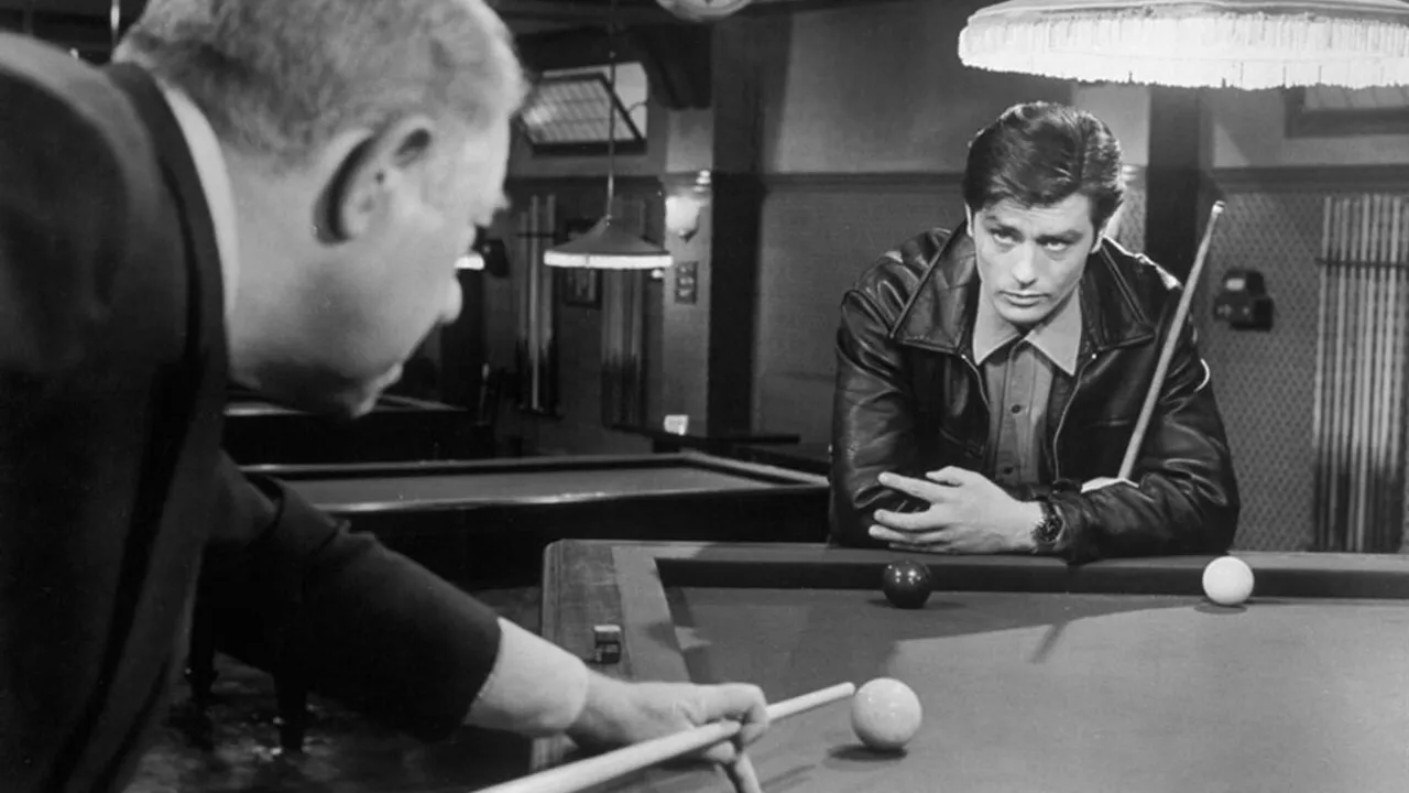 Dos hombres junto a una mesa de billar en una escena en blanco y negro de película clásica.