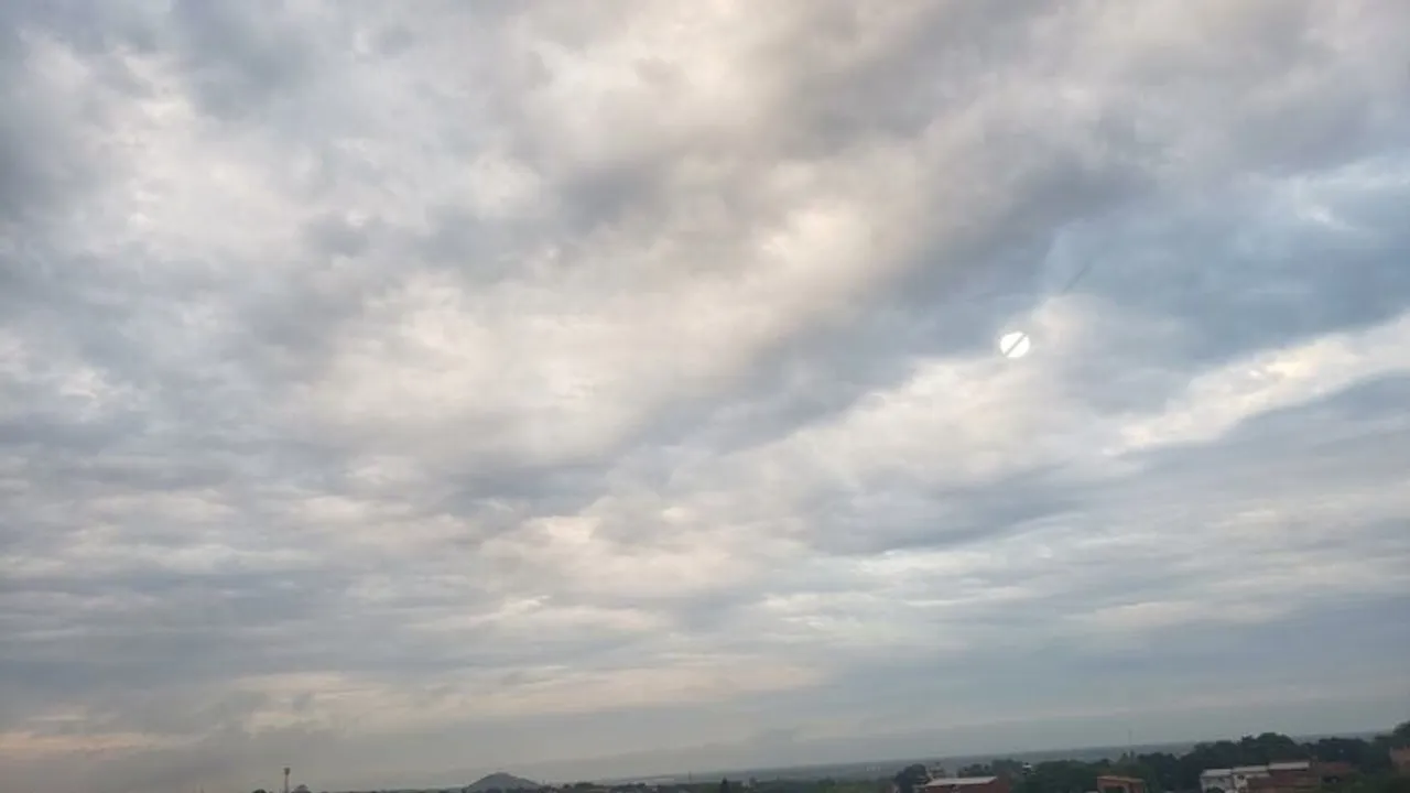 Cielo cubierto con nubes densas y grisáceas donde el sol apenas asoma en el horizonte urbano.