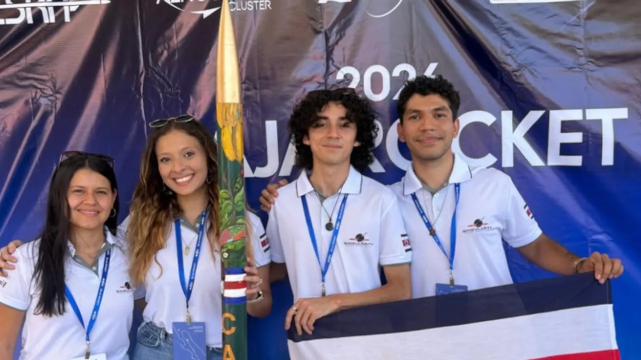 Cuatro integrantes del equipo posan junto al cohete artesanal Cacique y la bandera de Costa Rica tras la competencia.