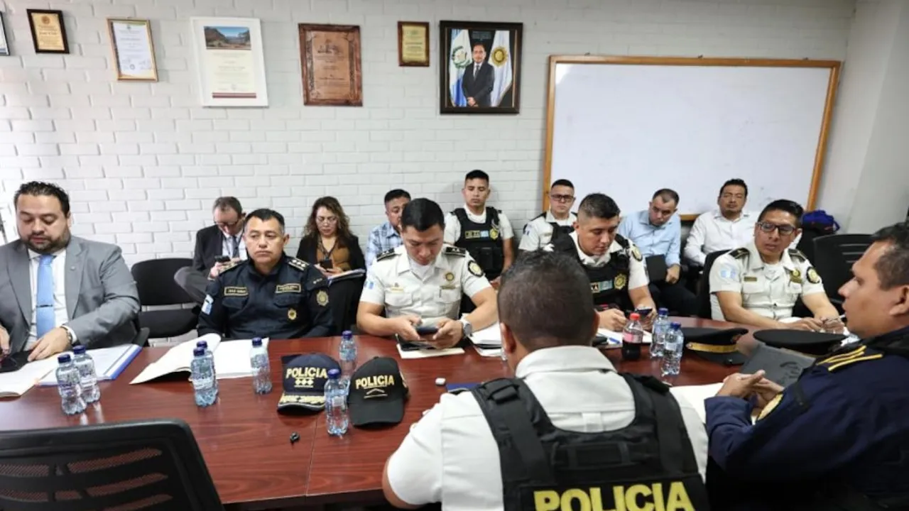 Autoridades y agentes policiales sentados alrededor de una mesa de reuniones revisando documentos y celulares.