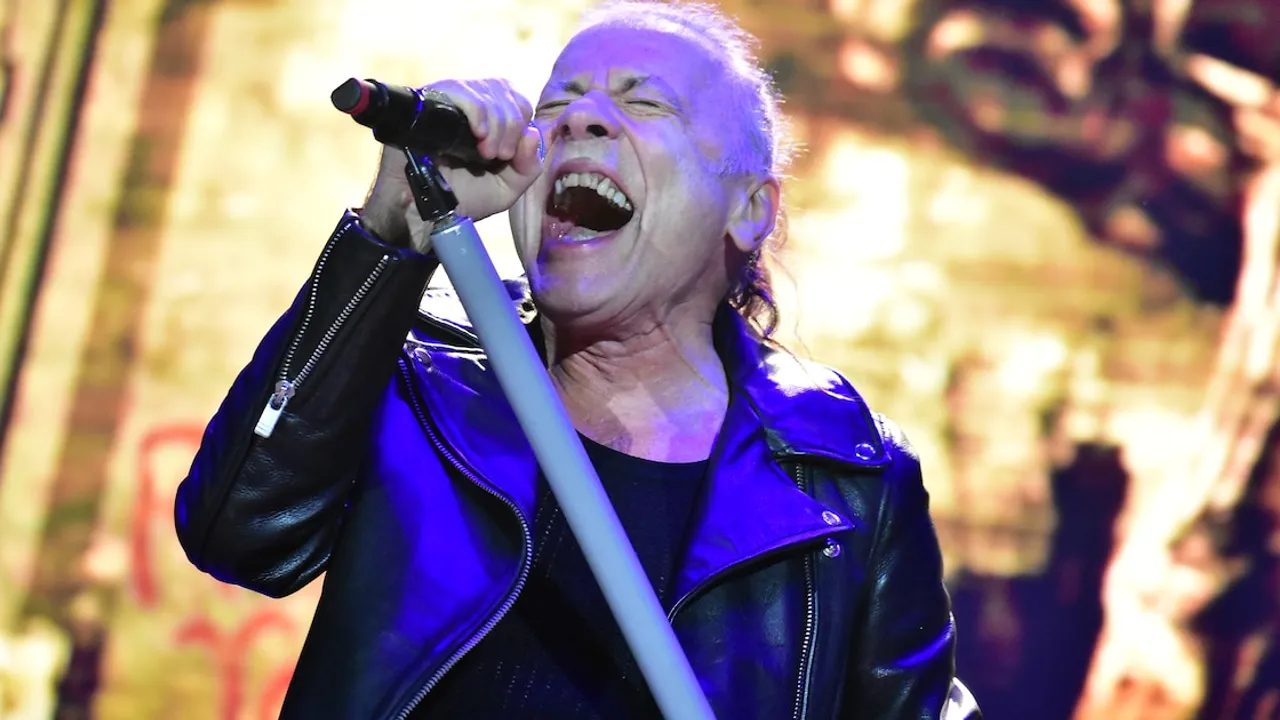 Bruce Dickinson canta con intensidad sosteniendo el micrófono durante el recital en el estadio salvadoreño.