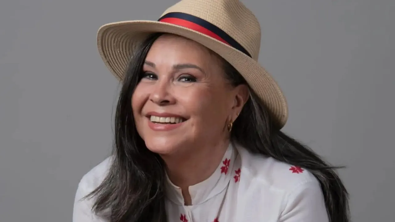 Lizza Bogado sonríe con un sombrero de paja con cinta tricolor y una blusa blanca con bordados rojos.