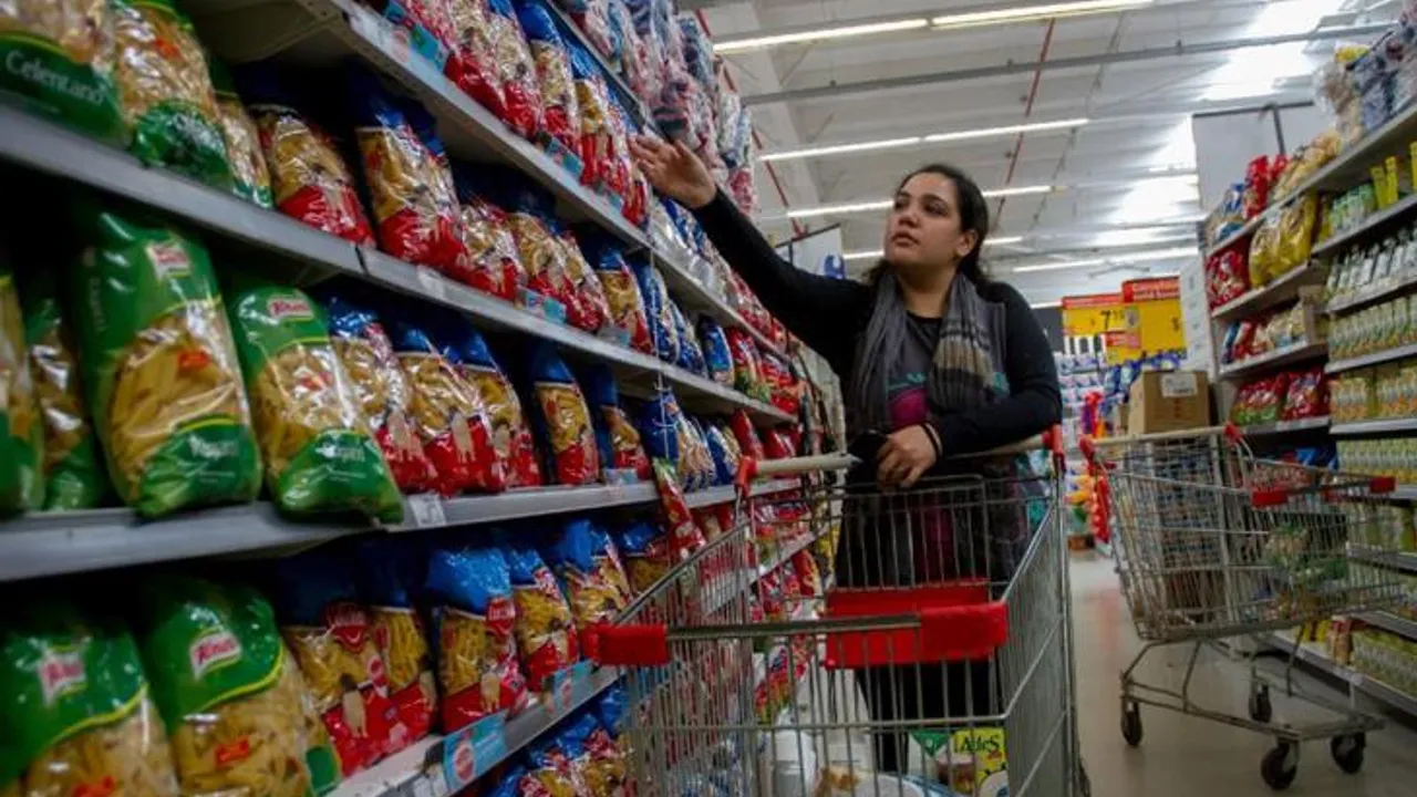 Mujer eligiendo productos en los estantes de un supermercado junto a un carrito de compras