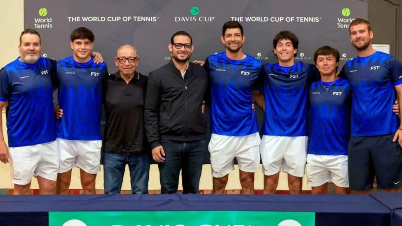 Integrantes del equipo salvadoreño de tenis posan con indumentaria deportiva frente al cartel oficial de Copa Davis.