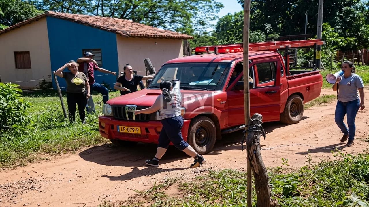 Vecinos confrontan una camioneta roja utilitaria en un camino de tierra vecinal en zona rural.