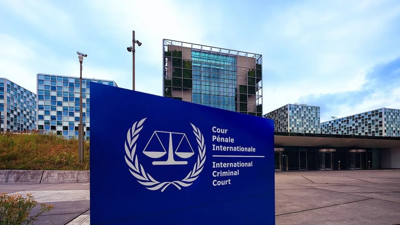 Cartel azul con el emblema de la Corte Penal Internacional frente al complejo de edificios de la sede judicial en La Haya.