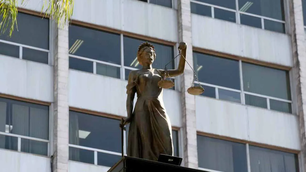 Estatua de la Justicia frente a la fachada acristalada de la sede del Poder Judicial