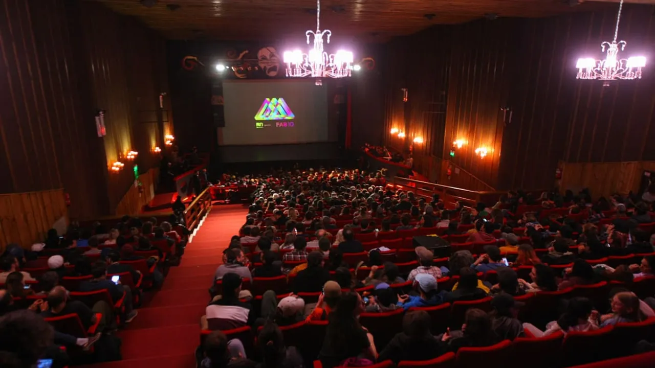 Sala de cine con público en butacas rojas mirando hacia la pantalla durante un festival audiovisual.