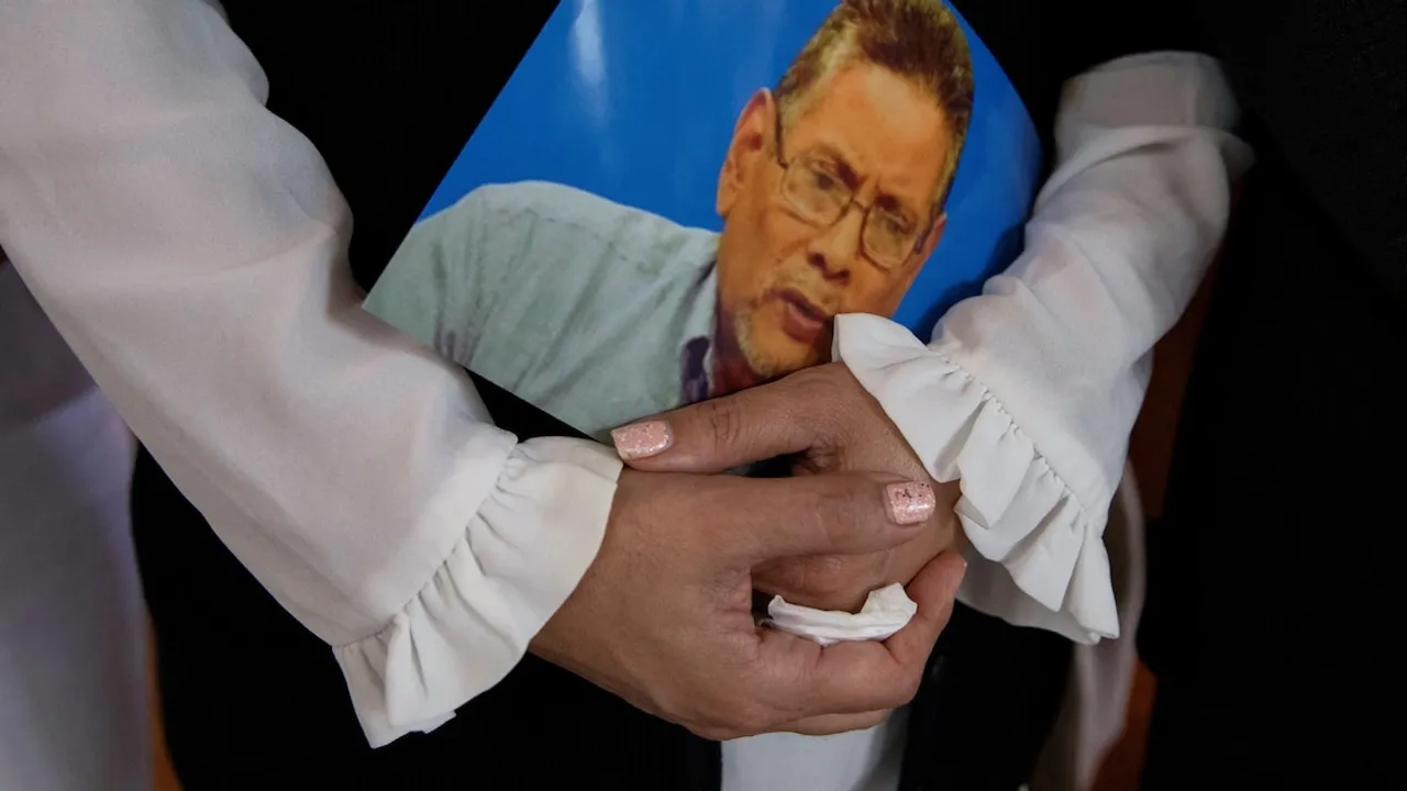 Manos de una mujer sostienen la fotografía de Roberto Samcam durante un acto de homenaje y pedido de justicia.