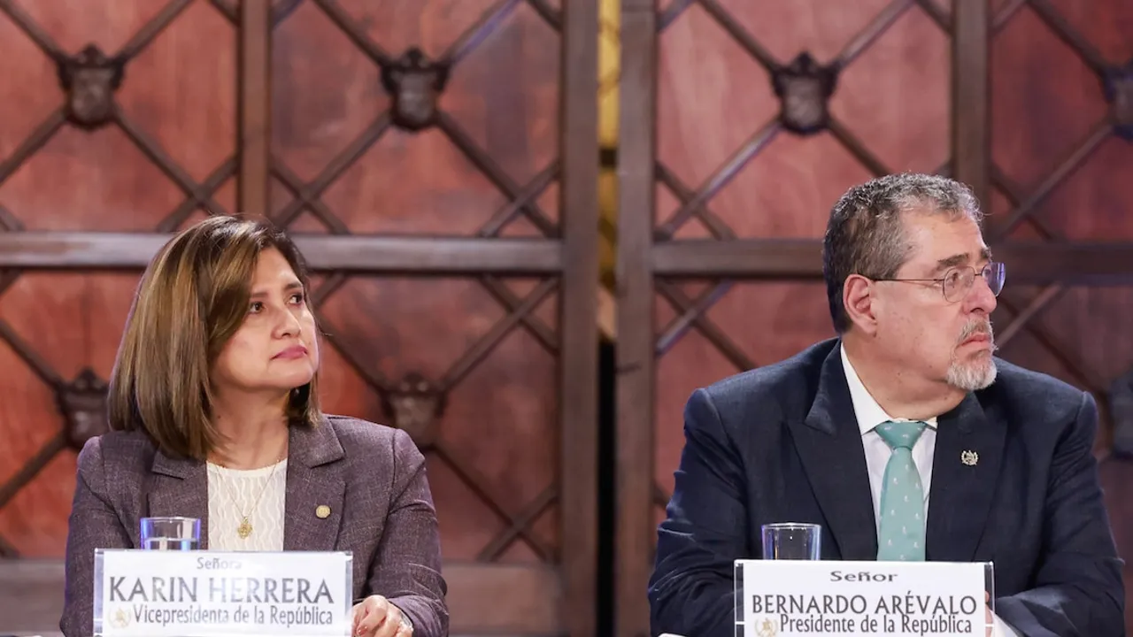 Bernardo Arévalo y Karin Herrera sentados juntos detrás de una mesa con carteles con sus nombres y cargos.