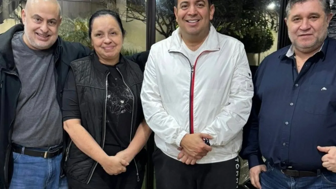 Cuatro dirigentes políticos posan de pie y sonrientes en un salón interior antes de los comicios.