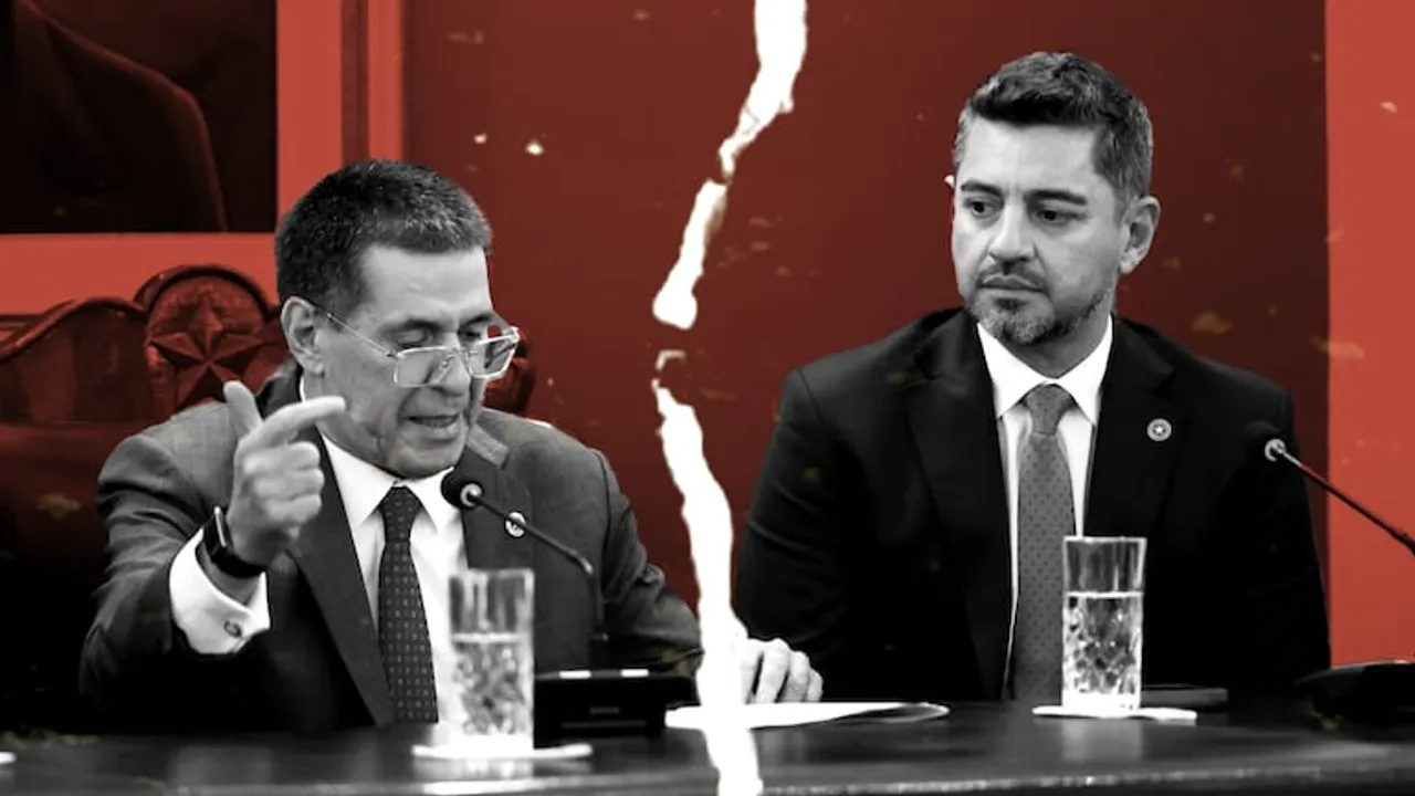 Dos hombres de traje sentados en una mesa oficial con micrófonos, divididos por un efecto visual de papel rasgado.