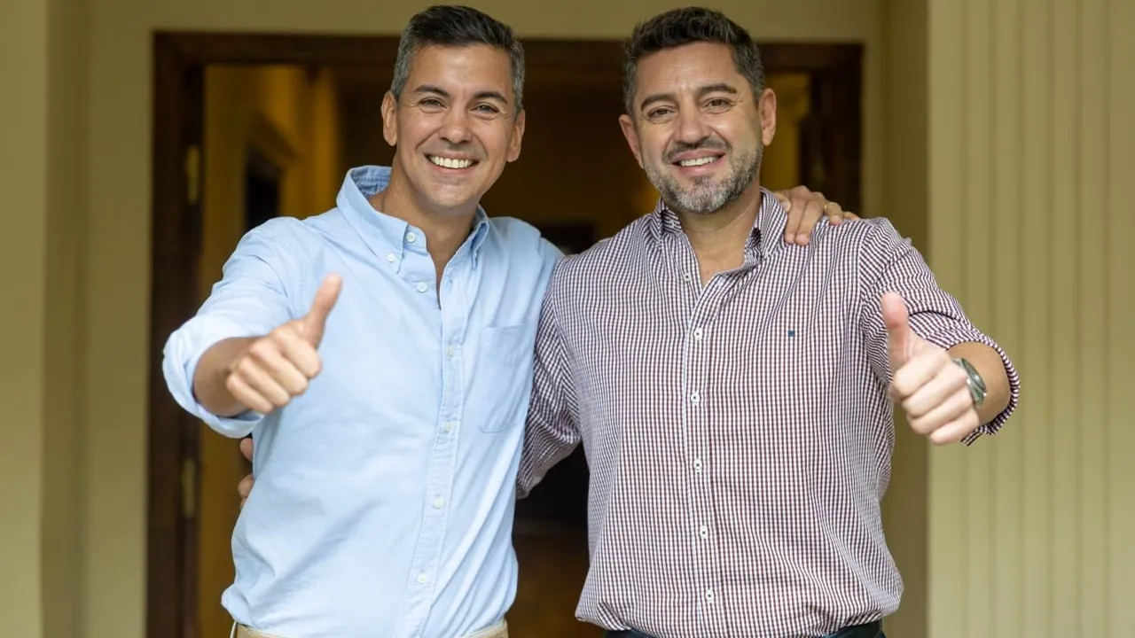 Santiago Peña y Pedro Alliana sonríen y levantan los pulgares vestidos con camisas casuales.
