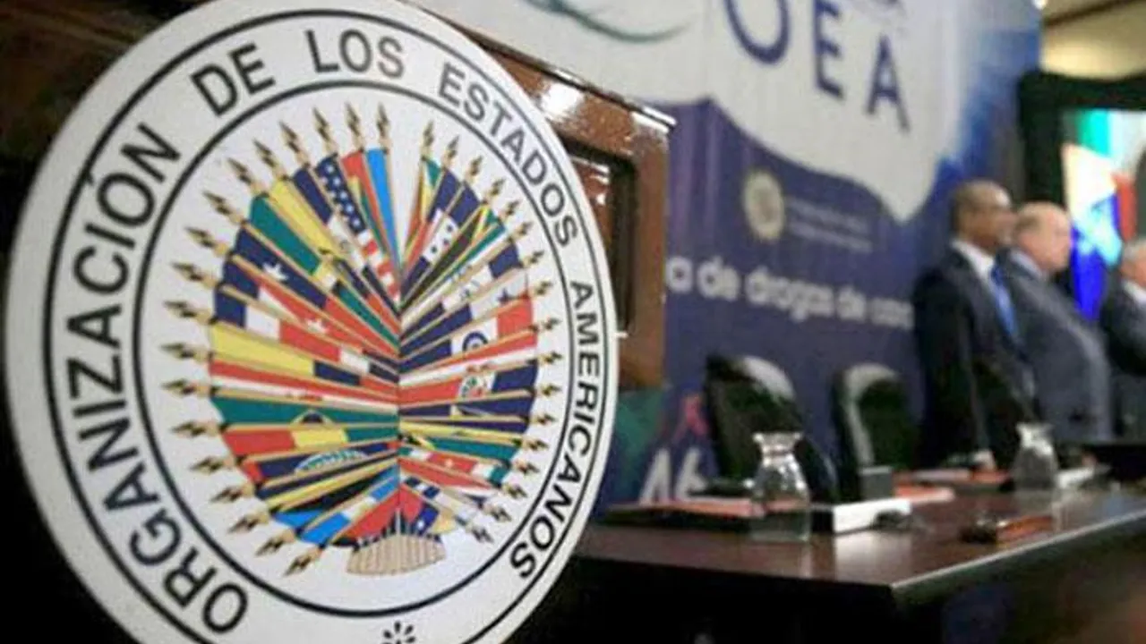 Emblema oficial de la Organización de los Estados Americanos en un estrado durante una reunión multilateral.