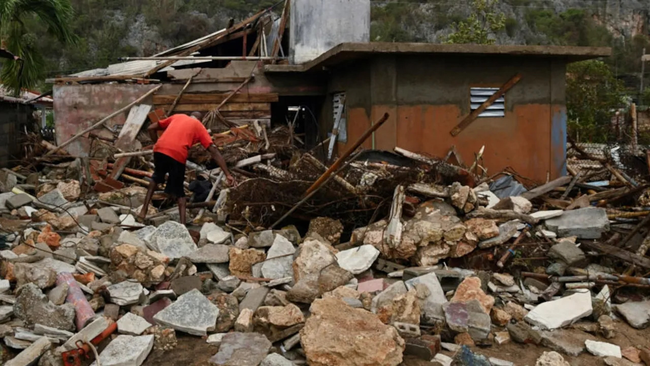 Hombre con remera roja camina entre escombros de piedras y restos de casas destruidas tras el paso de un temporal.