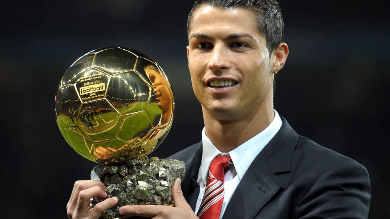 El futbolista portugués Cristiano Ronaldo posa sonriente sosteniendo su trofeo del Balón de Oro.