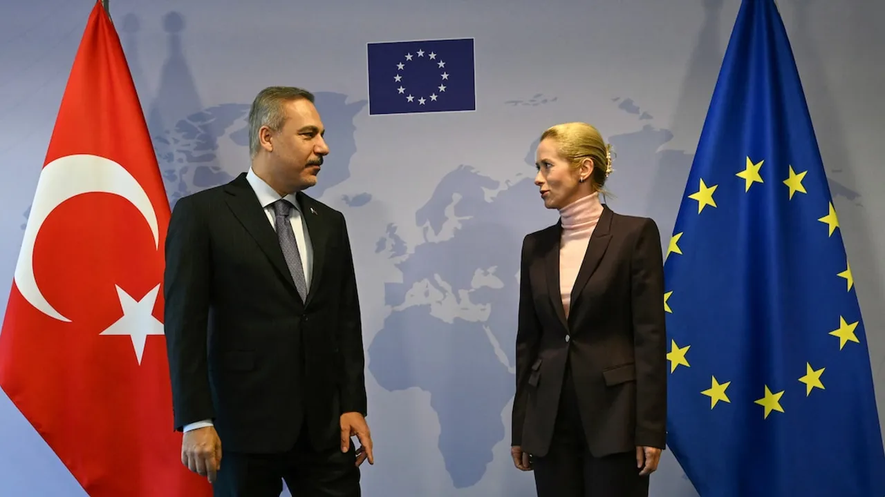 El canciller turco y una diplomática europea conversan de pie frente a banderas de Turquía y la Unión Europea