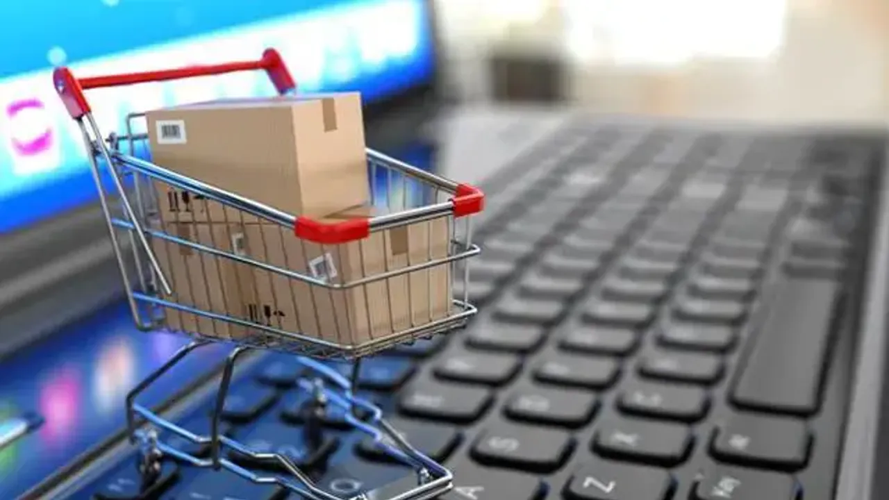 Carrito de compras en miniatura con paquetes de encomienda sobre el teclado de una computadora portátil.