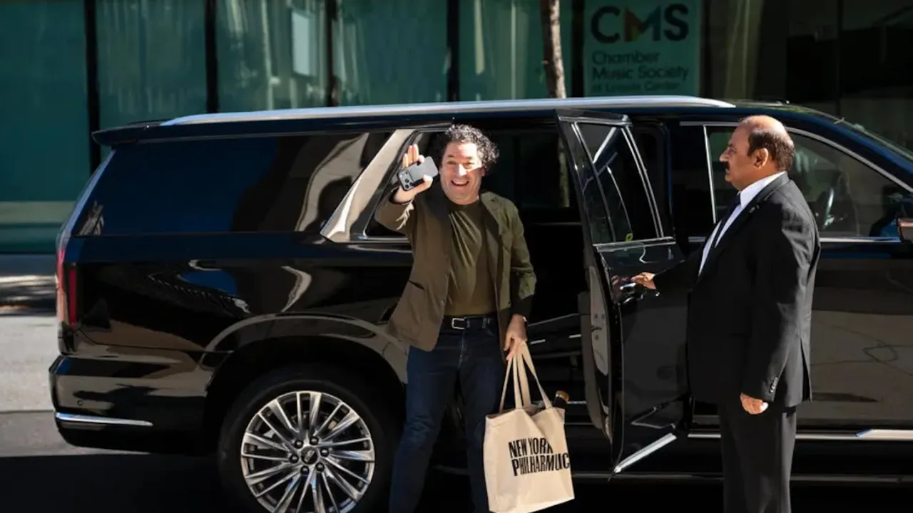 Gustavo Dudamel saluda desde una camioneta con un bolso de tela de la Filarmónica de Nueva York