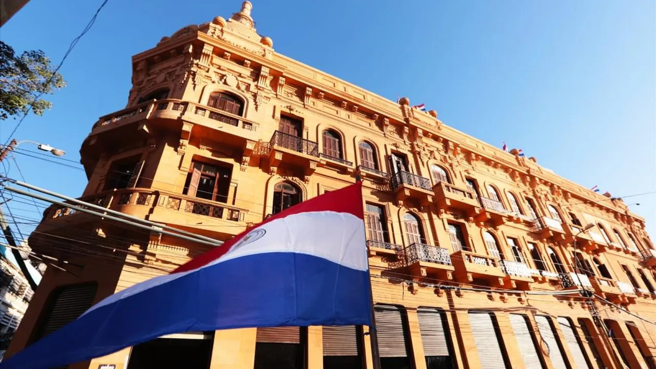 Edificio histórico del microcentro asunceno con balcones ornamentados y una bandera paraguaya flameando en primer plano.