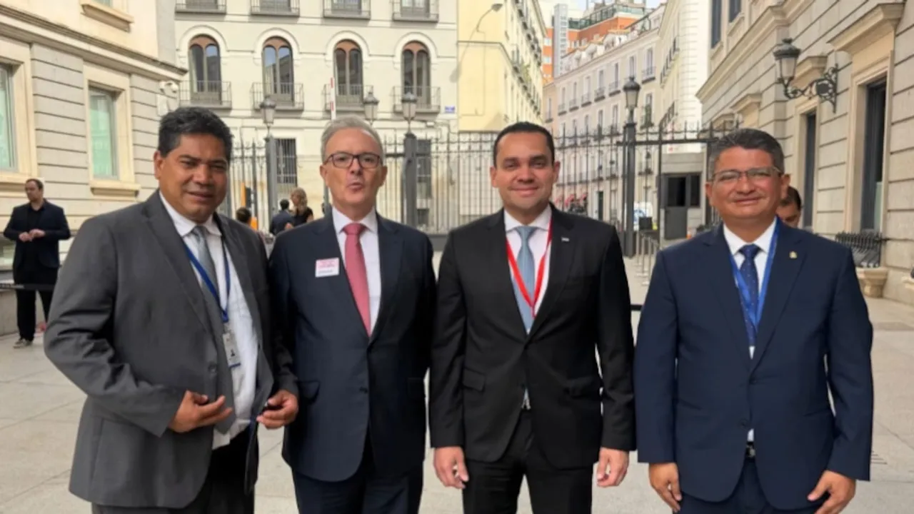 Cuatro hombres con trajes formales y corbatas posan sonrientes en el exterior de un edificio institucional en Madrid.
