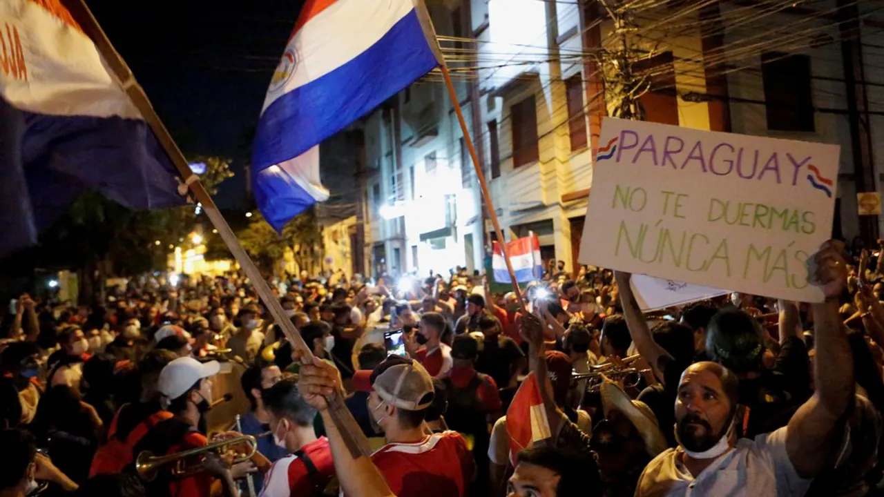 Manifestantes con banderas paraguayas y un cartel que dice Paraguay no te duermas nunca más durante una marcha nocturna.