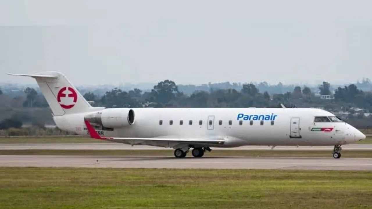 Avión comercial de color blanco con letras azules y detalles rojos en pista de aterrizaje