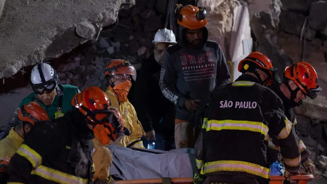 Bomberos con cascos de seguridad y uniformes de rescate trasladan una camilla entre escombros de una estructura colapsada.