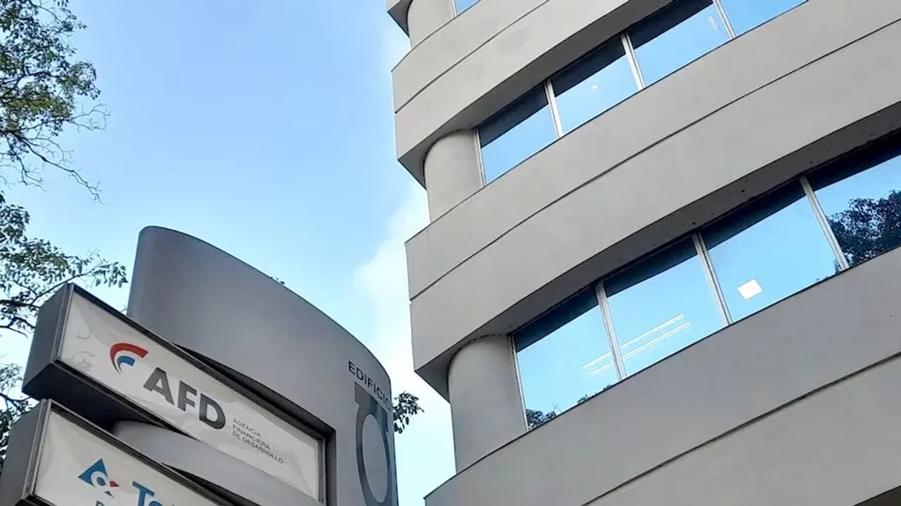 Fachada y cartel institucional del edificio de la Agencia Financiera de Desarrollo con ventanales y árboles.