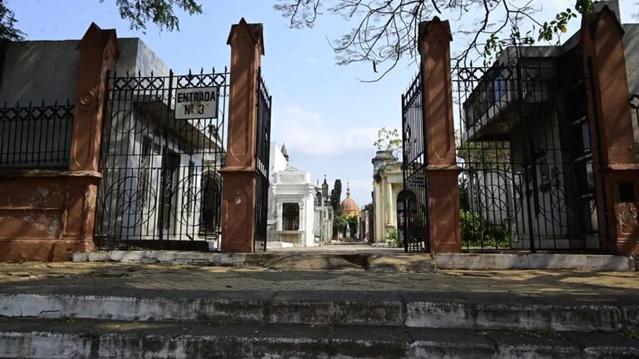 Portón de hierro negro abierto en el acceso número tres de un cementerio con panteones históricos