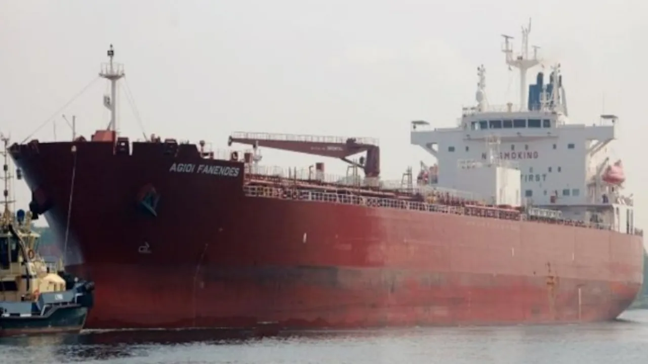 Buque petrolero de gran porte con casco rojo navegando en aguas abiertas asistido por un remolcador