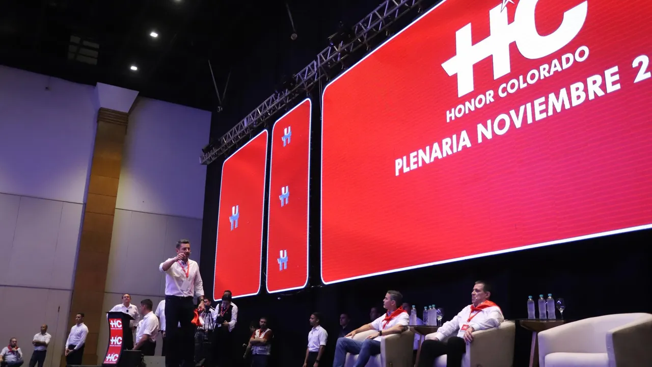 Autoridades sobre un escenario con una gran pantalla roja que exhibe el emblema de Honor Colorado en Asunción.