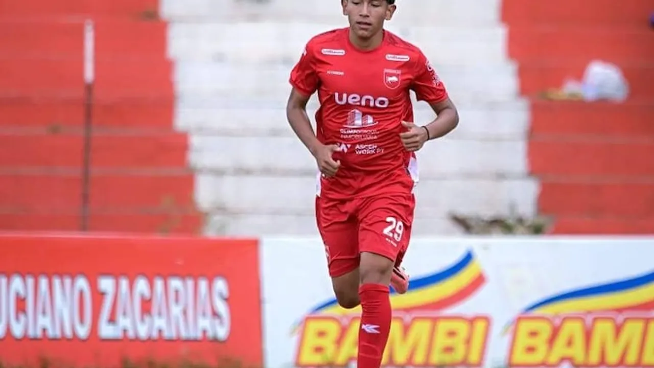 Joven futbolista de Paraguarí AC con camiseta roja corriendo sobre el campo de juego durante un partido.
