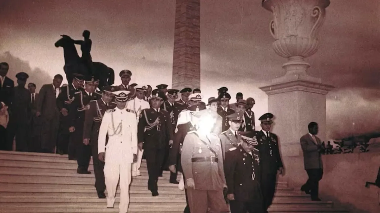 Militares de uniforme de gala bajan una escalinata exterior frente a un monumento y obelisco.