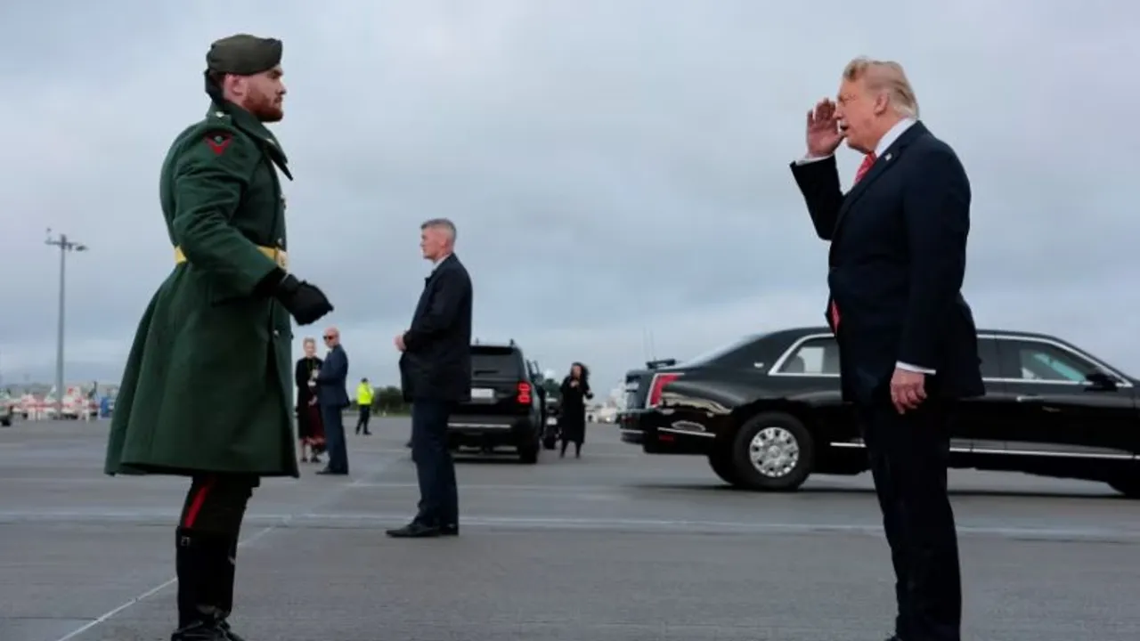 Donald Trump con traje oscuro realiza un saludo militar frente a un guardia con abrigo verde en una pista de aterrizaje.
