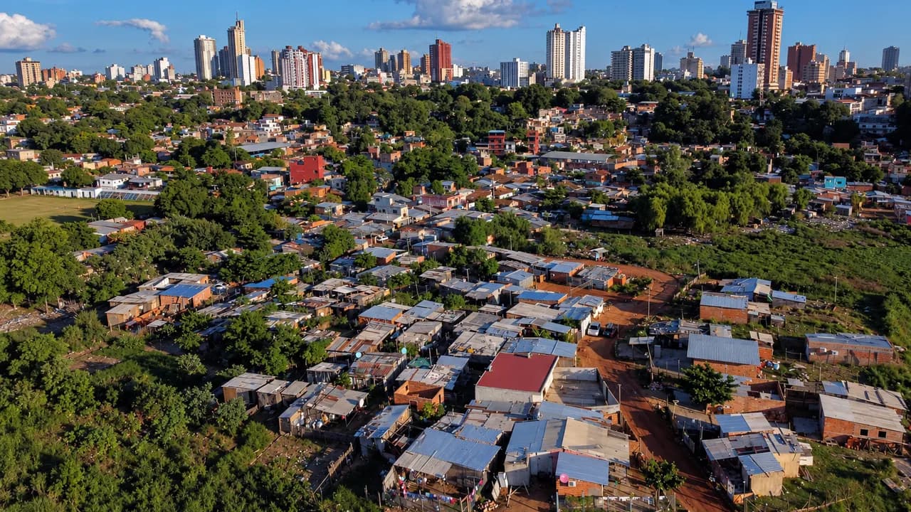 Viviendas precarias de un asentamiento urbano con edificios modernos en el horizonte de la ciudad.