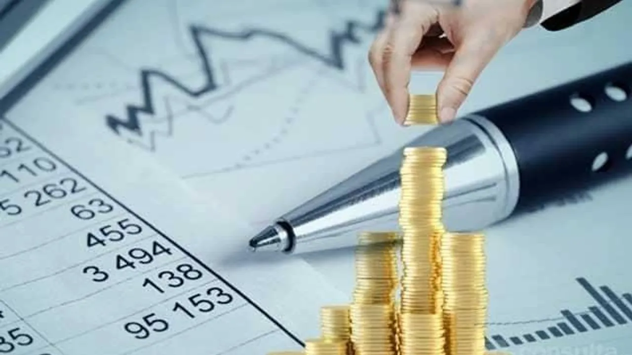 Monedas doradas apiladas en forma de gráfico ascendente junto a una lapicera y planillas contables financieras.