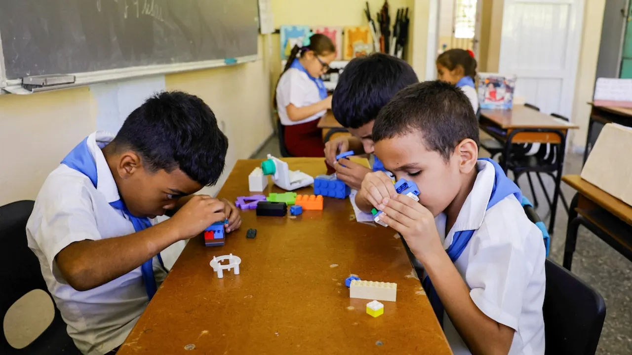 Niños con uniforme escolar manipulan bloques de construcción didácticos sobre una mesa en un aula con luz natural.