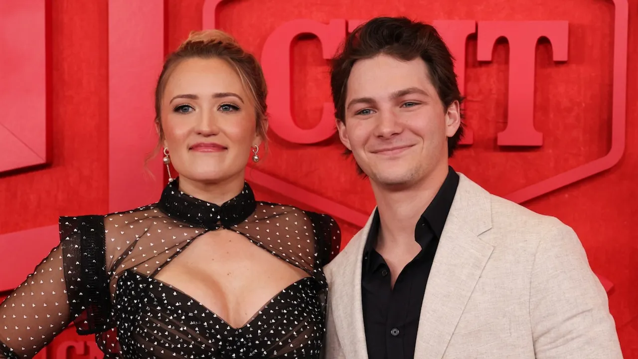 Emily Osment y Montana Jordan posan juntos sonrientes sobre un fondo rojo durante un evento oficial