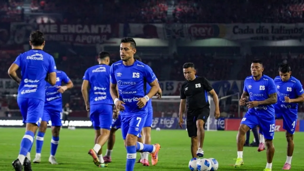 Futbolistas vestidos de azul entrenan en un campo de juego con balones mientras un integrante del cuerpo técnico observa.